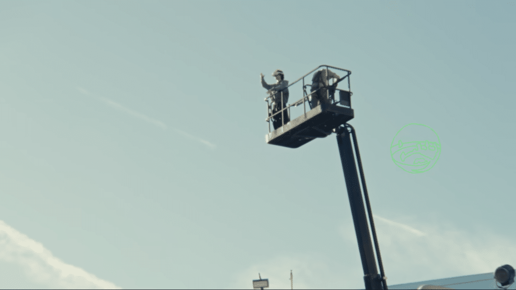 Two men stand on a mechanical crane.